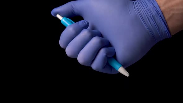 hand in blue medical protective gloves uses a ballpoint pen by pressing a button