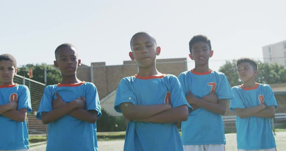 African American soccer kids in blue crossing arms and looking at camera in a sunny day