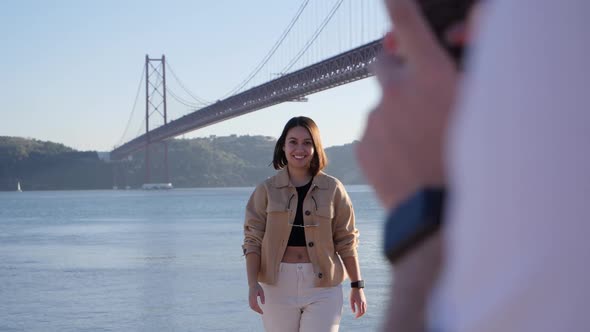 Influencer posing for photo in front of a famous bridge in Lisbon, Portugal