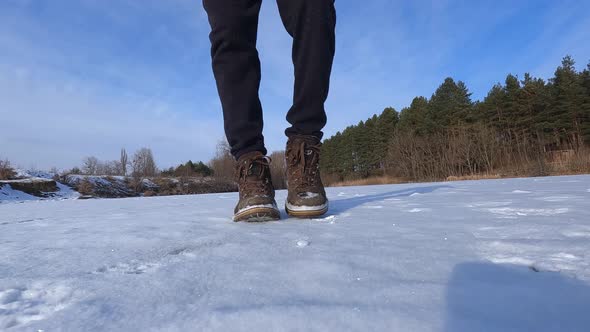 Men's shoes close up, steps on the snow time lapse shooting on a winter sunny day outdoors