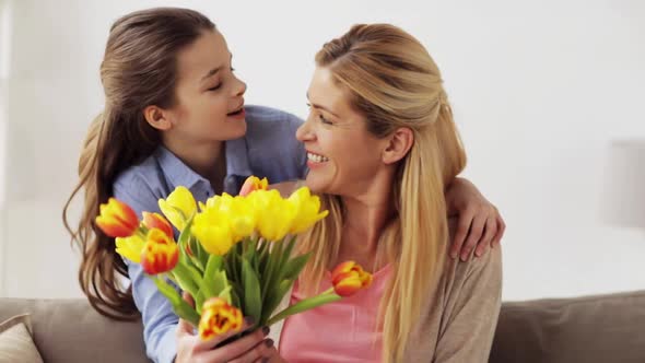 Happy Daughter Giving Flowers To Mother at Home