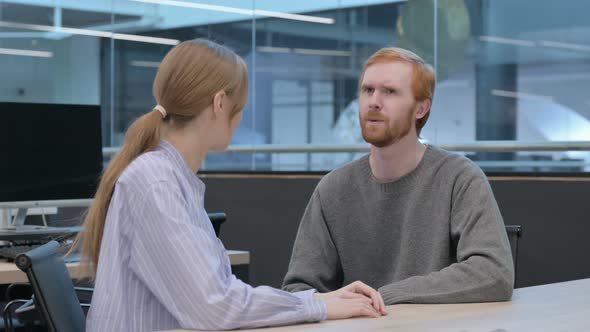 Young Man and Woman Having Discussion in Office