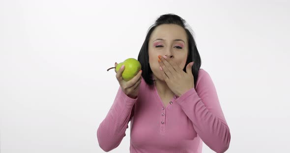 Young Beautiful Woman Eating Big, and Juicy Green Pear on White Background