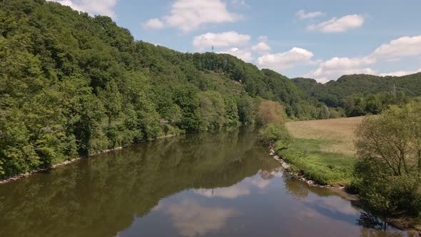 The calm Sieg river in Schladern, Germany on a beautiful sunny morning. Slow aerial fly over