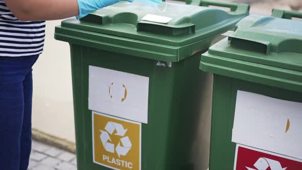 Unrecognizable Volunteer Putting Used Covid19 Face Mask in Plastic Container for Separate Trash