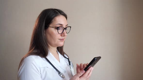 Doctor Texts Message on Mobile Phone Near Clinic Beige Wall