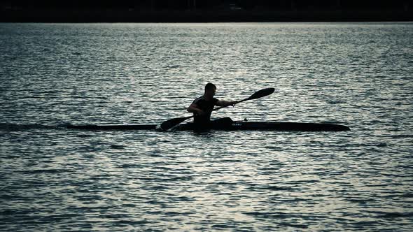 Sillouette of man kayaking on lake