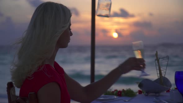 A man and woman couple dine and drink champagne on a tropical island beach