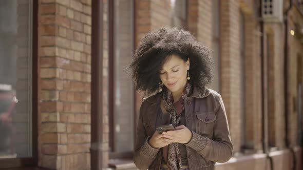 Portrait of Stylish Young African American Woman Viewing Information on Phone