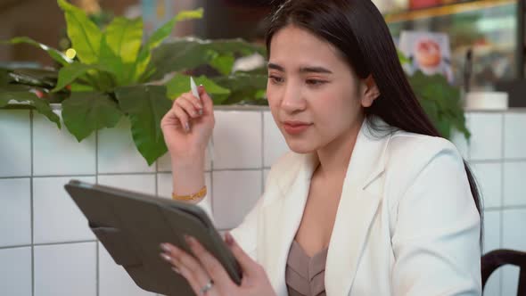 Thoughtful business woman thinking over future business plan at coffee shop, taking notes in tablet