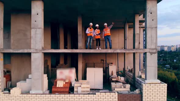 Working Engineers Stand in a Building, Discussing Construction.