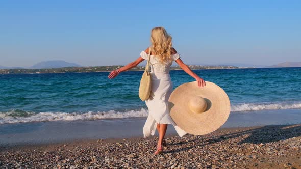 Woman Wearing Straw Hat and White Dress on Shoreline at Spetses Greece