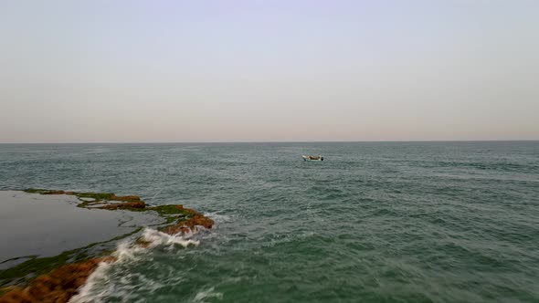 Fly pass a single fishing boat sailing forward at sea, aerial drone shot