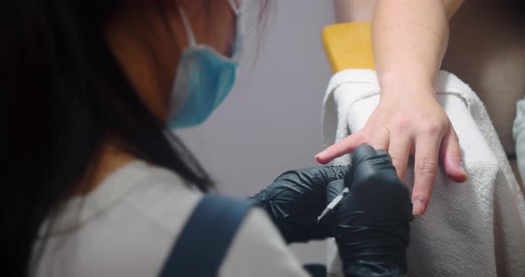 Young Brunette in a Beauty Salon Gets a Manicure and Pedicure in a Salon a Girl Does a Manicure to a