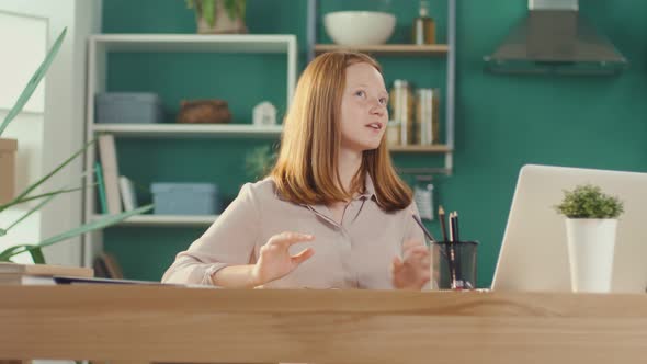 Redhaired Teenage Girl Studying at Home Online Watching a Video Tutorial