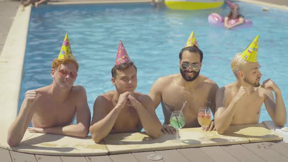 Four Positive Friends Dancing in Water at Poolside on Sunny Summer Day. Portrait of Cheerful Young