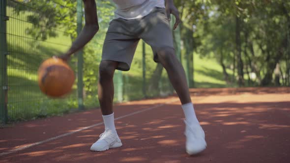 Young Unrecognizable African American Basketball Player Hitting Ball on Court. Sportive College alt