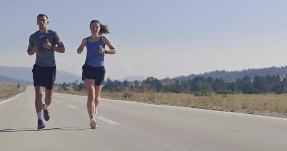 Tracking Slow Motion Shot of Sportive Couple Jogging Outdoors in the Morning Trail Running