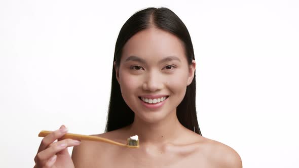 Happy Chinese Lady Holding Toothbrush Cleaning Teeth Over White Background