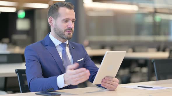 Video Call on Tablet By Middle Aged Businessman at Work