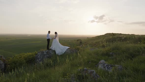 Beautiful Couple Stand on Big Rock Hold Hands Together