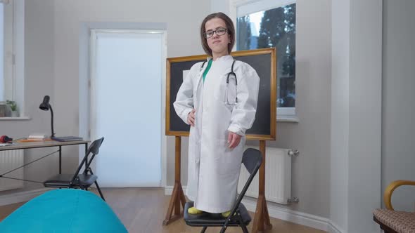 Zoom in to Confident Caucasian Doctor Little Person in Eyeglasses and Medical Gown Crossing Hands