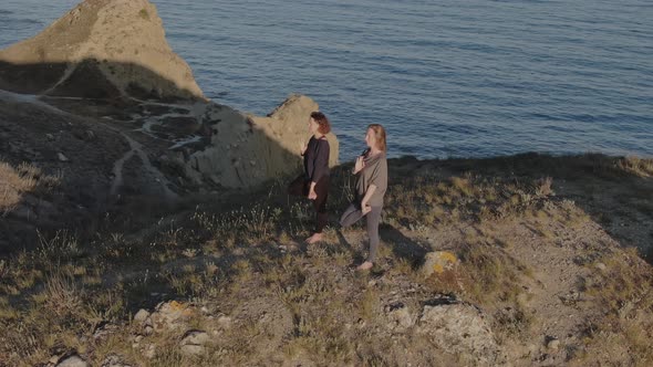 Two Women in Sportswear and Barefoot Doing Yoga on the Grass By the Sea