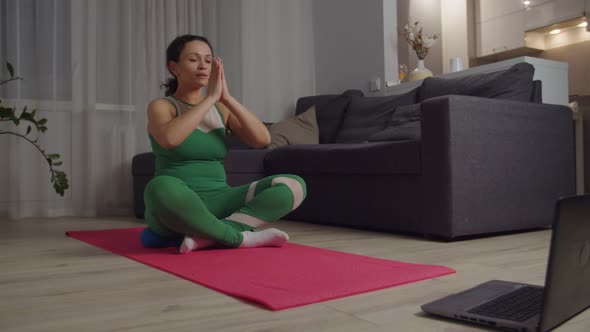 Woman Doing Namaste While Practicing Meditation Using Laptop Indoors