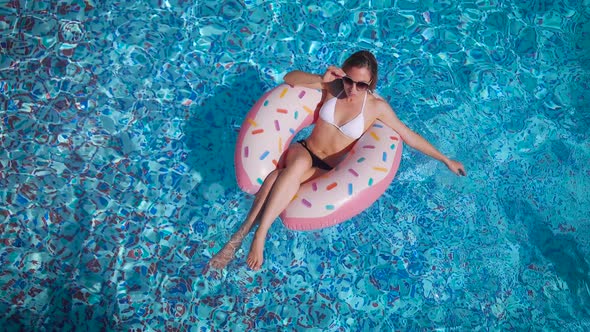 A Beautiful Young Woman Swims in the Pool on an Inflatable Circle. Rest at the Resort.