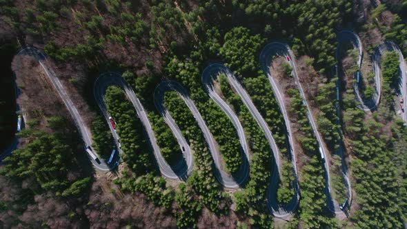 Slow aerial rise above traffic on winding road of Bratocea Pass, Romania