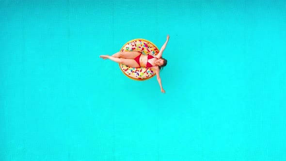 Aerial View of a Woman in Red Bikini Lying on a Donut in the Pool