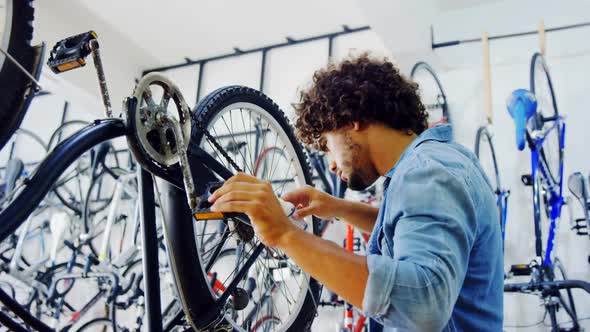 Mechanic repairing bicycle in workshop