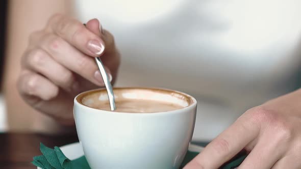 Girl is Stirring Coffee with a Spoon While in a Cafe Spoons Drop Coffee Drops in a Mug Closeup Slow