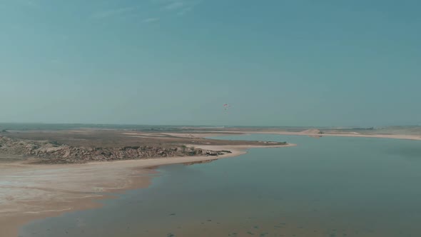 Aerial View Of Motorised Paraglider Flying Over Salt Lake In The Distance