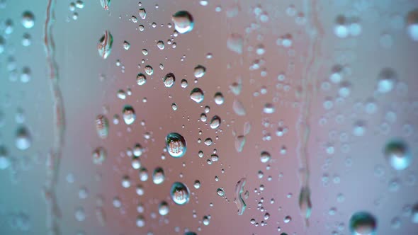 Big raindrops on glass window background. Slow motion of water drops flowing on the glass in a rainy