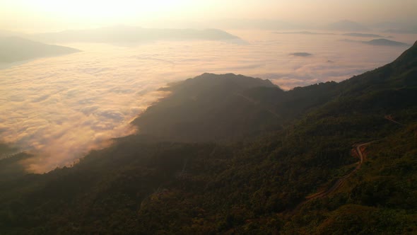 4K Flying through the clouds above mountain tops. Tropical forest with smoke and fog.