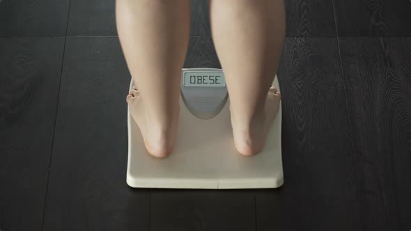 Woman Stepping on Scales, Word Obese Appearing on Screen, Problems With Weight
