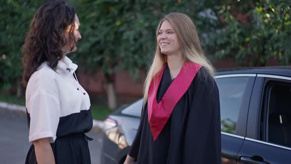 Smiling Grateful Daughter in Graduation Gown Hugging Mother Talking Smiling Sitting in Car in Slow