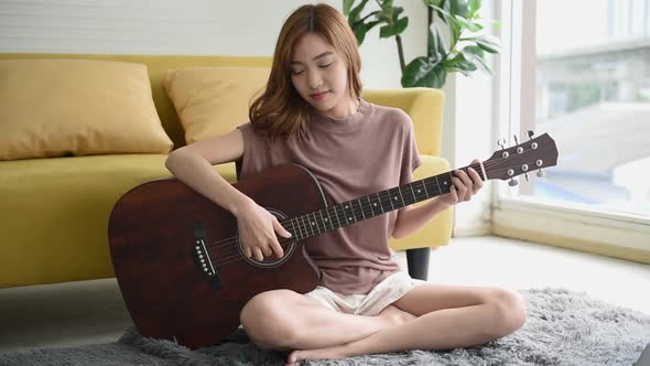 Asian woman playing the guitar with happy