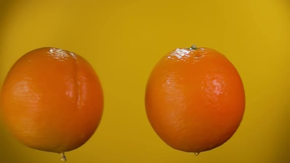 Two Juicy Oranges are Flying and Colliding with Each Other Rising Drops of Water