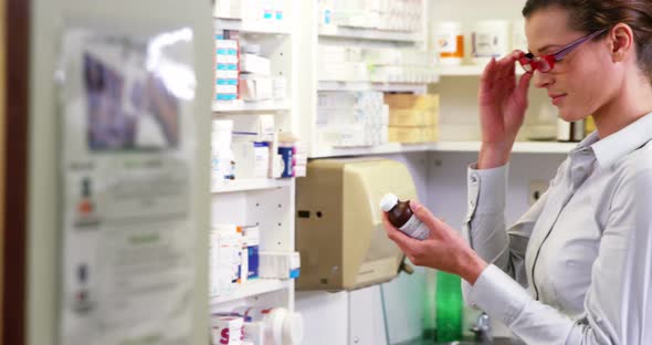 Pharmacist checking a bottle of drug in pharmacy