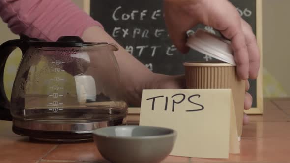 Pouring takeout coffee in cafe near tipping jar medium shot