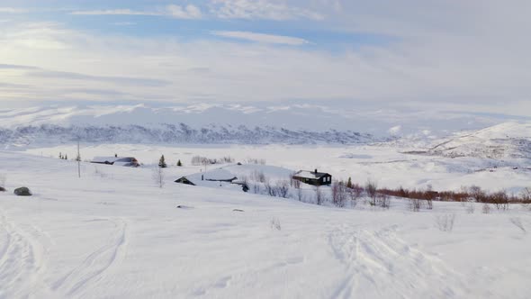 Mountainside Cabins And Snowy Mountain Landscape In Winter In Norway - aerialing shot