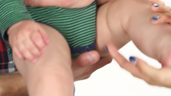 Parent Hands Touch the Baby's Legs. White. Close Up