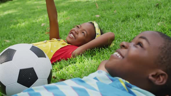 Animation of happy african american siblings lying on lawn and looking at sky