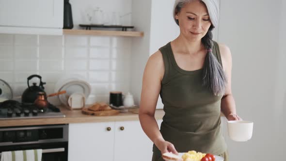 Asian mature woman brings her breakfast to the table