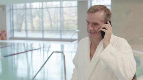 Elderly Man Having Phone Call in Indoor Pool