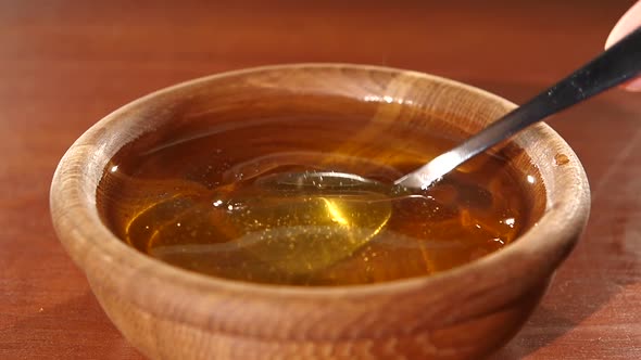 Taking Honey By Metal Spoon in Wooden Bowl, Slow Motion