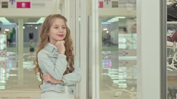 Cute Little Girl Smiling To the Camera, Examining Fashion Store Display