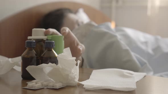 Close-up of Medical Bottles Standing at the Table at Hospital Bed As Blurred Caucasian Woman Taking